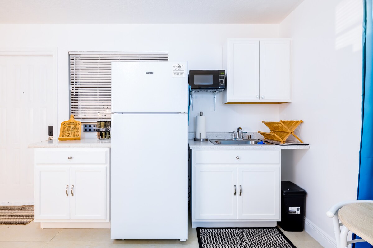 Kitchenette blanca con refrigerador y microondas